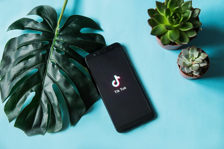a phone showing the tiktok label surrounded by plants